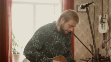 Gitar çalan ve prova sırasında şarkı söyleyen adam.