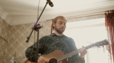 Gitar çalan ve prova sırasında şarkı söyleyen adam.