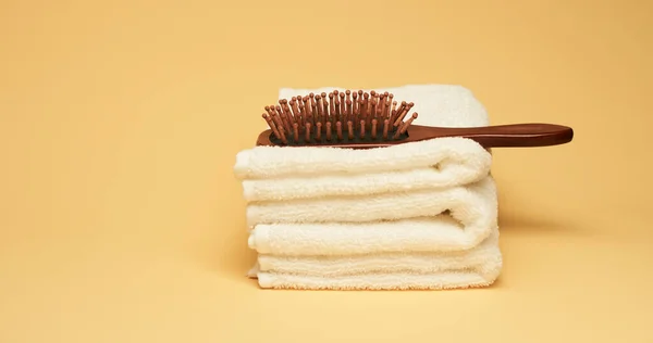 Hairbrush and towels at yellow background. Minimalistic wellness concept — Stock Photo, Image