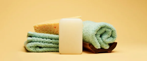 Akcesoria do kąpieli i spa. Mydło, ręczniki i gąbka na żółtym tle — Zdjęcie stockowe