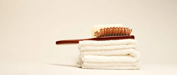 Hairbrush and towels at light background. Minimalistic wellness concept — Stock Photo, Image