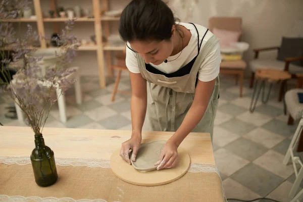 Vrouw die kleiplaat vormt in aardewerk werkplaats — Stockfoto