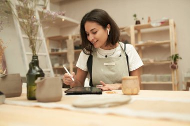 Stüdyoda çalışan tabletli ve kulaklıklı bir seramistim.