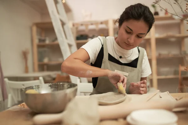 Artisan shaping clay plate with sponge — Stock Photo, Image