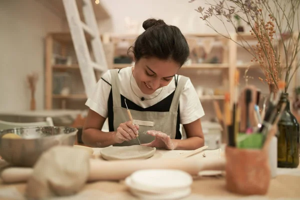 Female ceramist shaping clay plate — Stock Photo, Image