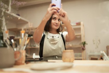 Genç zanaatkar stüdyoda selfie çekiyor.