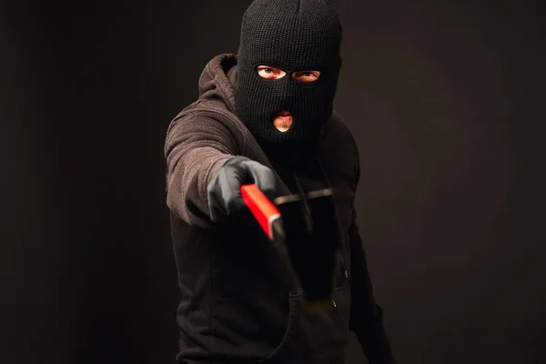 Грабитель держит металлический лом на черном фоне — стоковое фото
