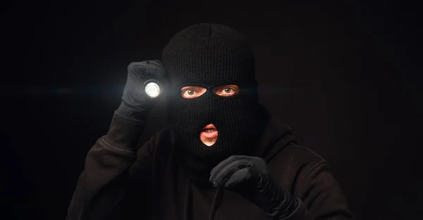 Maskerad inbrottstjuv med ficklampa på mörk rygg — Stockfoto