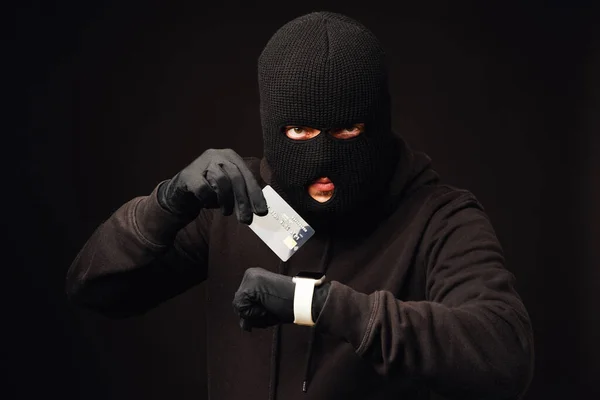 Anonymus thief holding credit card and phone. Internet or online banking hacking — Stock Photo, Image