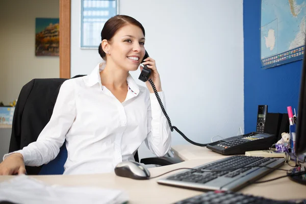Portrait of young businesswoman talking on phone in office — Stock Photo, Image