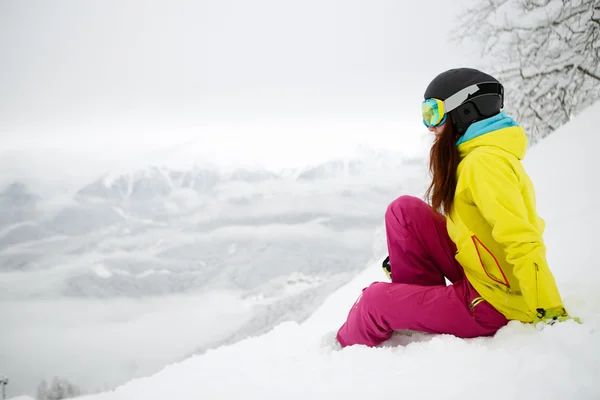 Snowboardzista kobieta siedzi na stoku góry śniegu — Zdjęcie stockowe