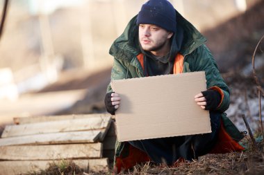 Evsiz bir adam, metniniz için boş karton tutan