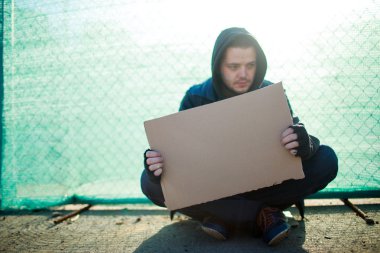 Evsiz bir adam, metniniz için boş karton tutan