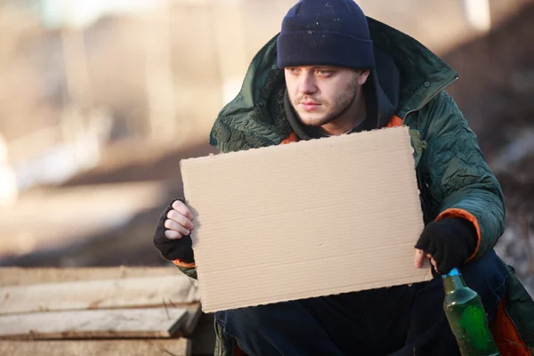 Homeless man holds blank cardboard for your text — Stock Photo, Image