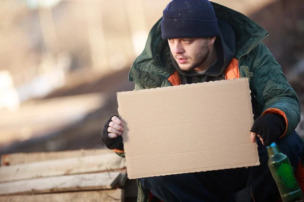 Homeless man holds blank cardboard for your text — Stock Photo, Image