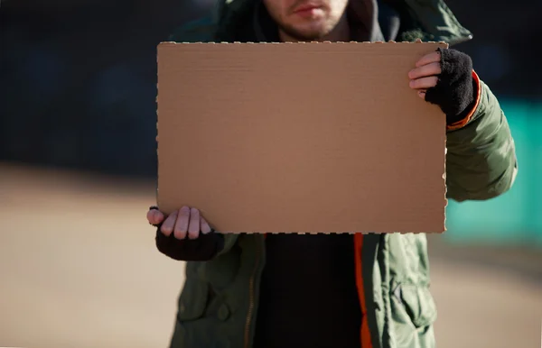 Homeless man holds blank cardboard for your own text — Stock Photo, Image