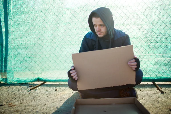 Homeless man holds blank cardboard for your text — Stock Photo, Image