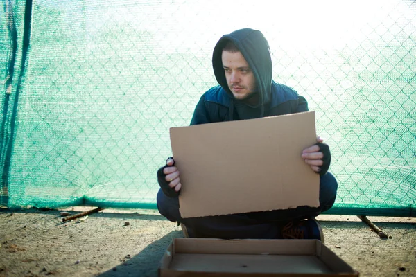 Homeless man holds blank cardboard for your text — Stock Photo, Image