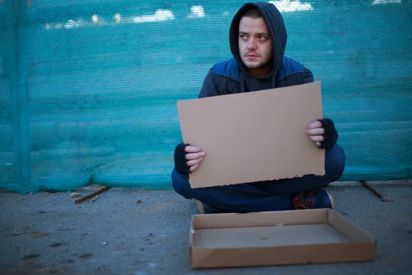 Homeless man holds blank cardboard for your text — Stock Photo, Image