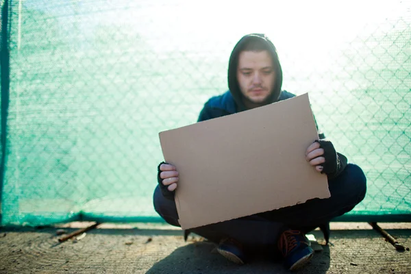 Homeless man holds blank cardboard for your text — Stock Photo, Image