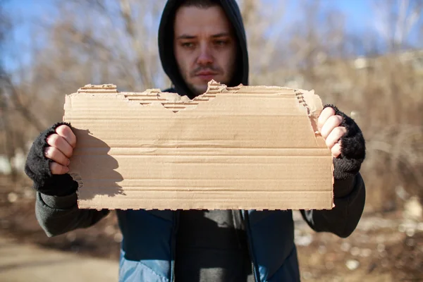 Homeless man holds blank cardboard for your text — Stock Photo, Image