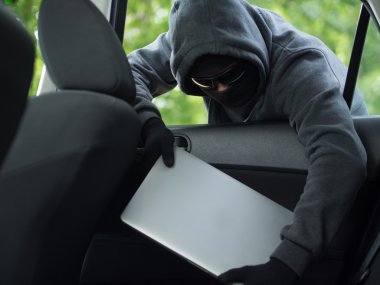 Car theft - a laptop being stolen through the window of an unoccupied car. clipart