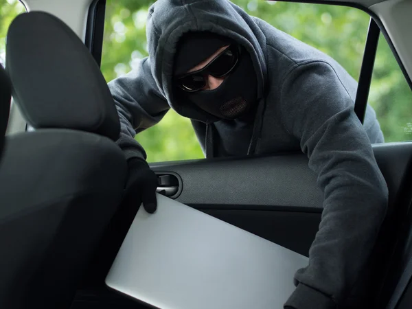 Roubo de carro - um laptop sendo roubado pela janela de um carro desocupado . — Fotografia de Stock