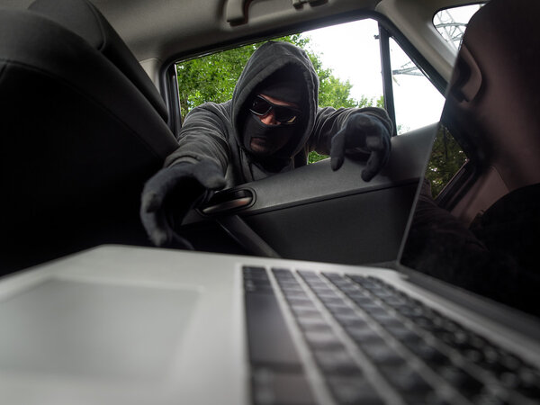 Crime concept - thief stealing laptop from the car. View from laptop