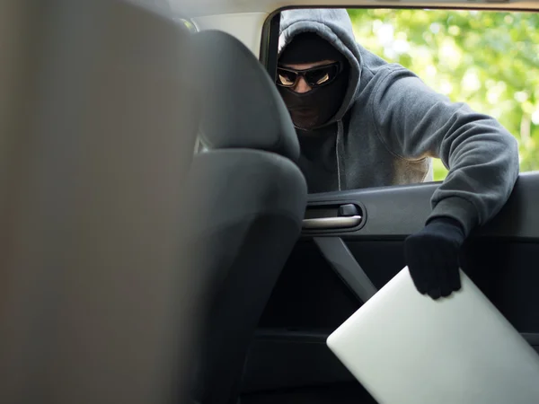 Araba hırsızlığı - boş bir araba pencereden varlık kaypak laptop. — Stok fotoğraf