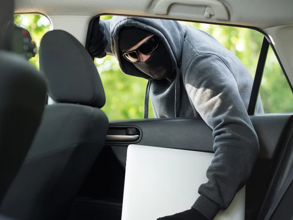 Κλοπή αυτοκινήτων - ένα laptop είναι κλεμμένα μέσα από το παράθυρο ένα μη κατειλημμένο αυτοκίνητο. — Φωτογραφία Αρχείου