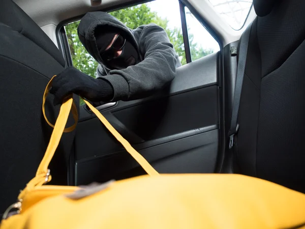 Koncepce dopravy zločinu. Zloděj ukradl tašku z auta — Stock fotografie