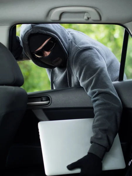 Robo de coche - un ordenador portátil que se roba a través de la ventana de un coche desocupado . — Foto de Stock