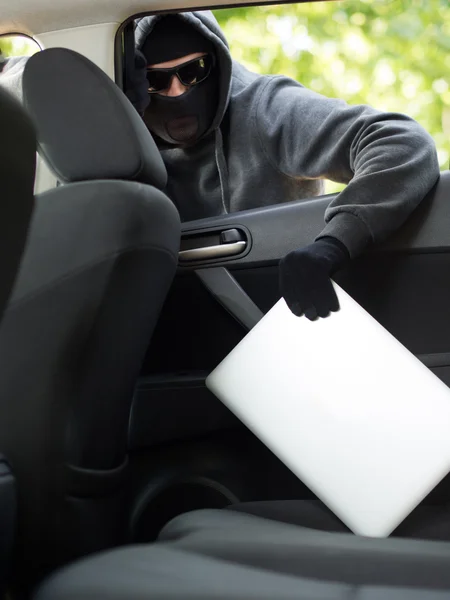 Roubo de carro - um laptop sendo roubado pela janela de um carro desocupado . — Fotografia de Stock