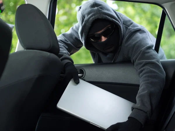 Robo de coche - un ordenador portátil que se roba a través de la ventana de un coche desocupado . — Foto de Stock