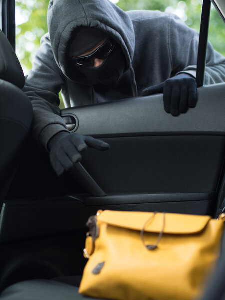 Transportation crime concept .Thief stealing bag from the car