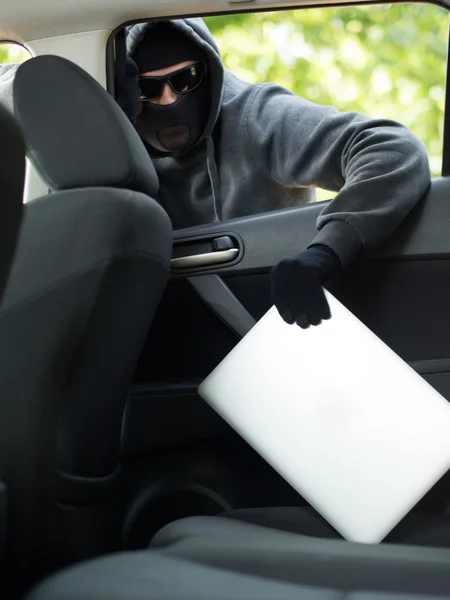 Autodiefstal - een laptop wordt gestolen door het raam van een leegstaande auto. — Stockfoto