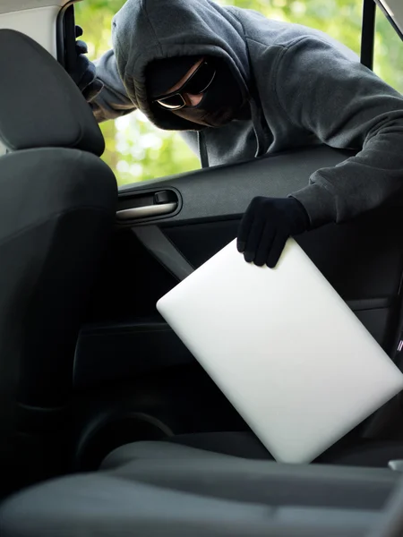 Kradzież samochodu - laptop trwający skradziony przez okno samochodu pustostanów. — Zdjęcie stockowe
