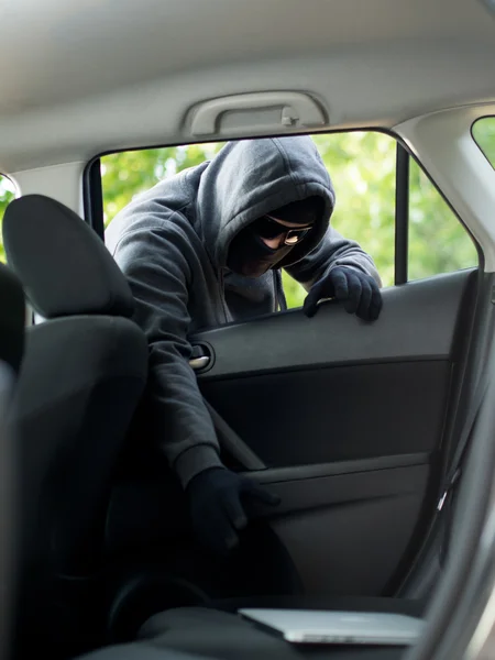 Car theft - a laptop being stolen through the window of an unoccupied car. Stock Photo