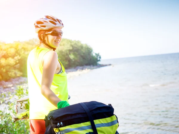 Junge Frau mit Fahrrad steht am Meer — Stockfoto