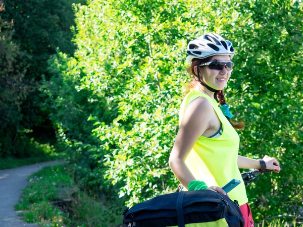 Mujer montando en bicicleta en el sendero del bosque en un día soleado —  Fotos de Stock