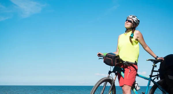 Woman with bicycle joyng sun on seaside and smiling — Stock Photo, Image