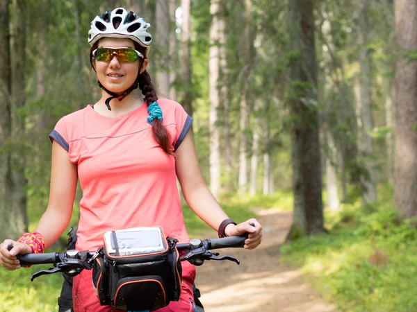 Mulher andando de bicicleta na trilha da floresta em dia ensolarado — Fotografia de Stock