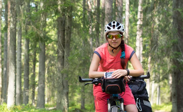 Woman riding a bike on the forest trail in sunny day — Stock Photo, Image