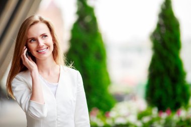 Cep telefonu ile genç güzel kadın. Şehir defocusrd arka plan.