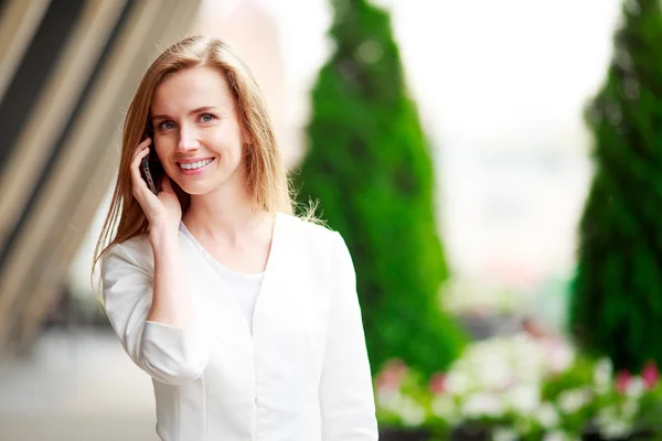 Jonge mooie vrouw met mobiele telefoon. Stad defocusrd achtergrond. — Stockfoto