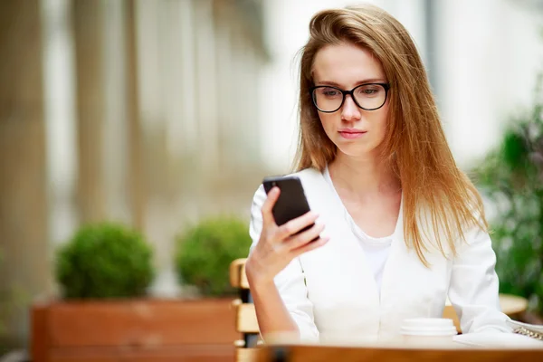 Ragazza che scrive sullo smart phone in una terrazza del ristorante con uno sfondo sfocato — Foto Stock