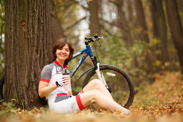 Woman sitting next to bike — Stock Photo, Image
