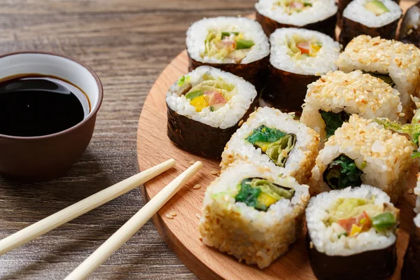 Sushi rolls with salmon and hot tea ceremony on black wooden table — Stock Photo, Image