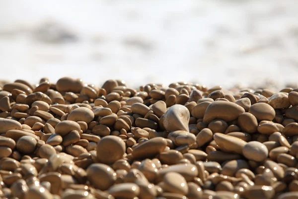Natte pebble tegen een zee surf — Stockfoto