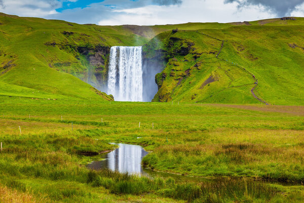 Skogafoss are reflected in small stream